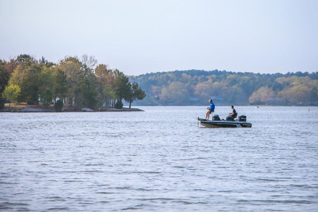 Two people fish from a motorboat on Lake Gaston, one of the best lakes in North Carolina for a family vacation.