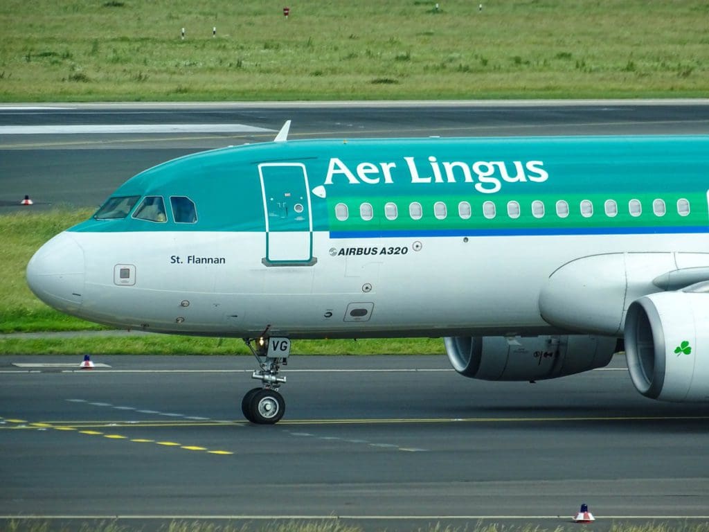A close up of the nose of an Aer Lingus plane parked on the jetway of an airport.