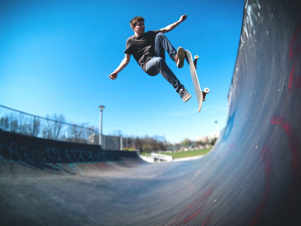 A teen boy skateboards on a half-pike course, one of the best extreme sports to do with teens on a family trip.