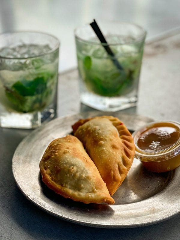 Two cocktails sit alongside empanadas at The Stone Soup Company in Ybor City.