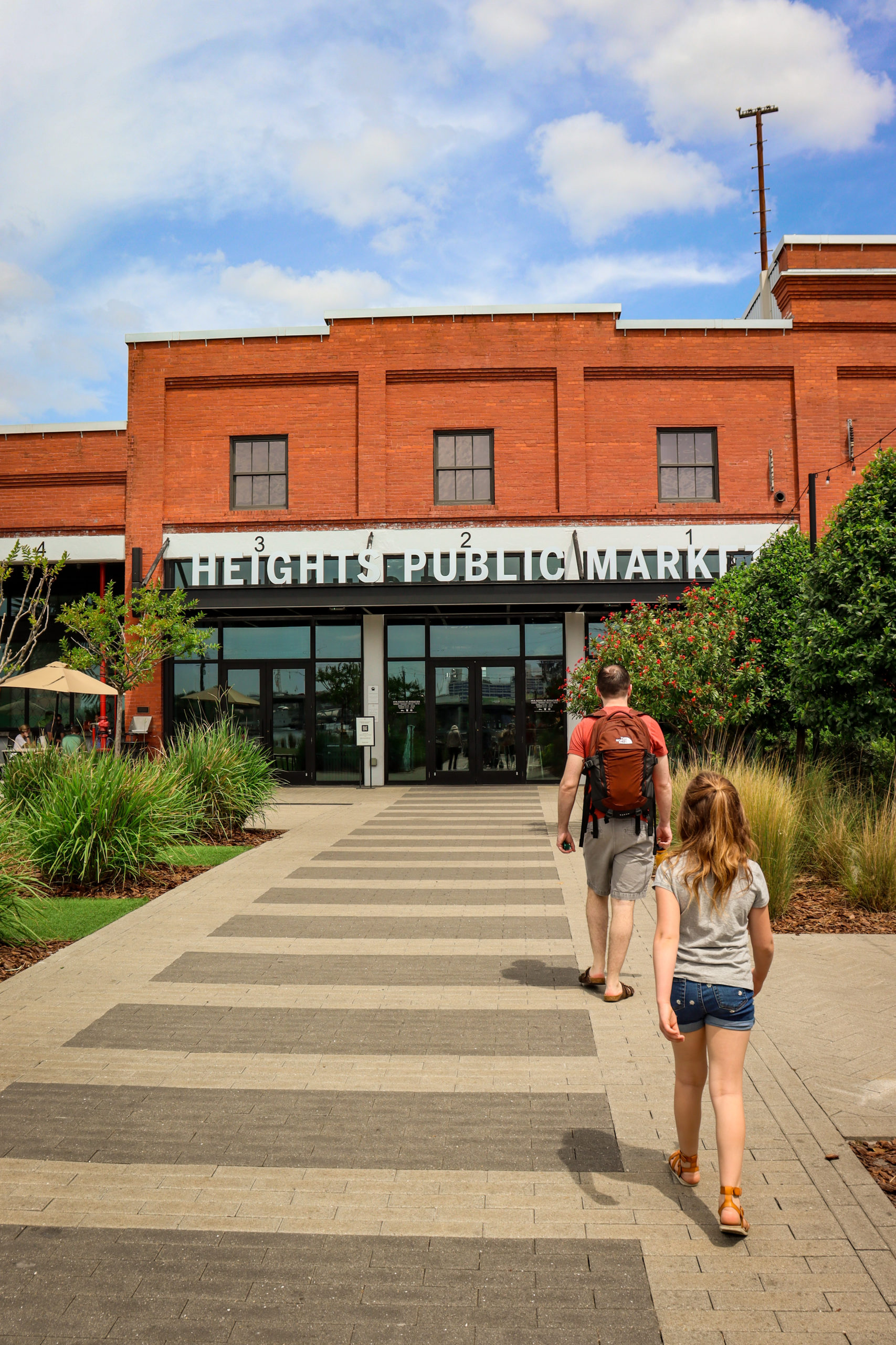 A dad and his young daughter walk toward Heights Public Market at Armature Works in Tampa Bay for lunch.