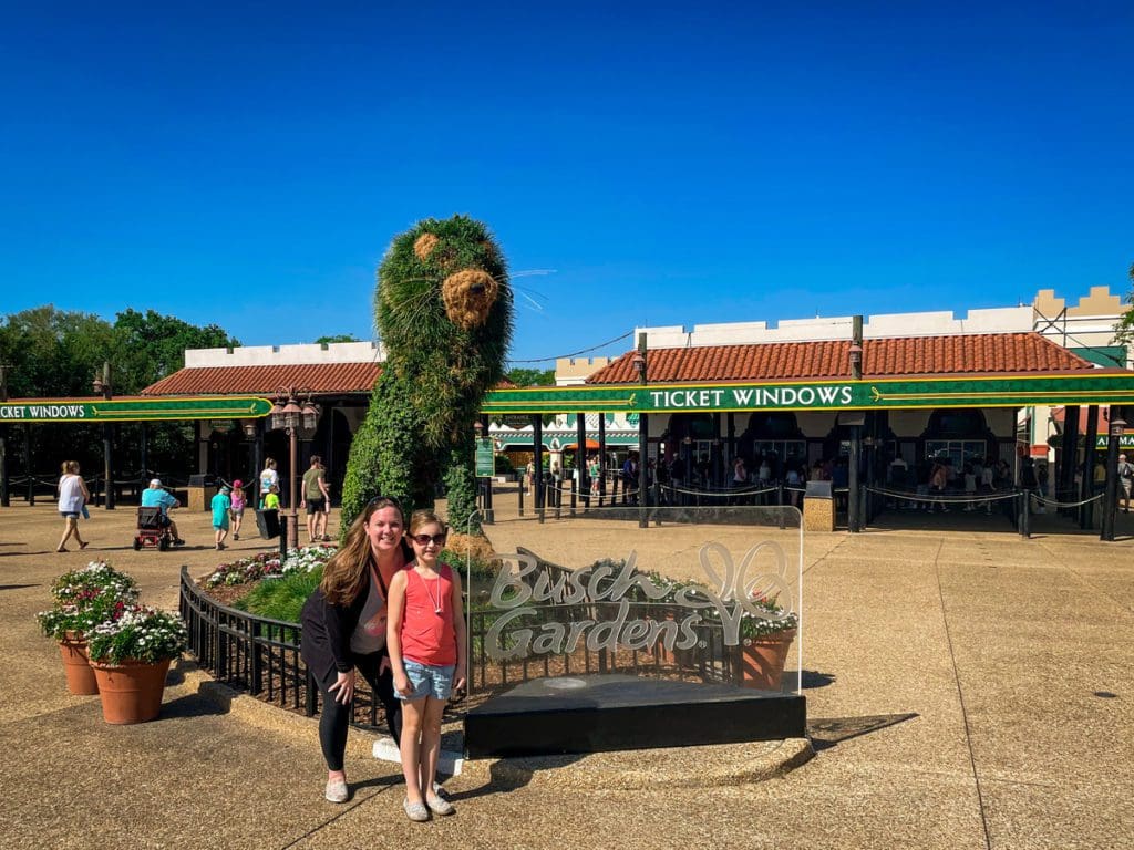 A mom and her young daughter pose in front of a sign at the entrance of Busch Gardens® Tampa Bay.