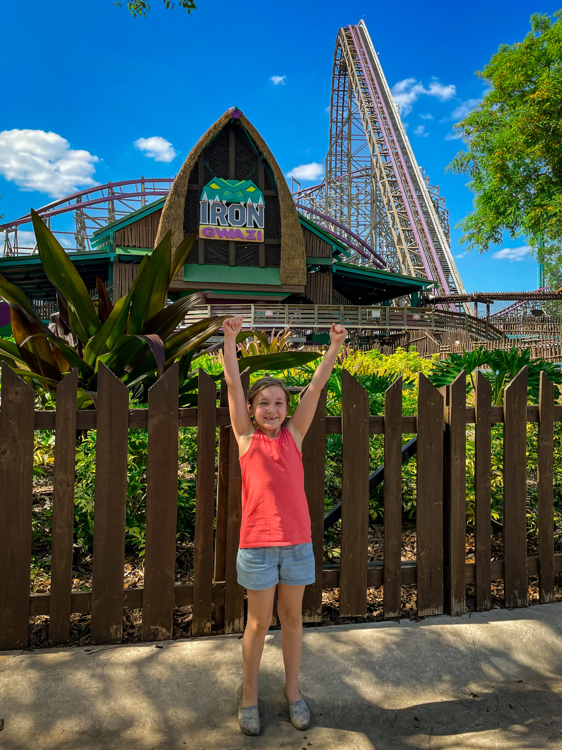 A young girl excitedly puts her hands in the air in front of Iron Gwazi, one of the thrilling rides at Busch Gardens® Tampa Bay.