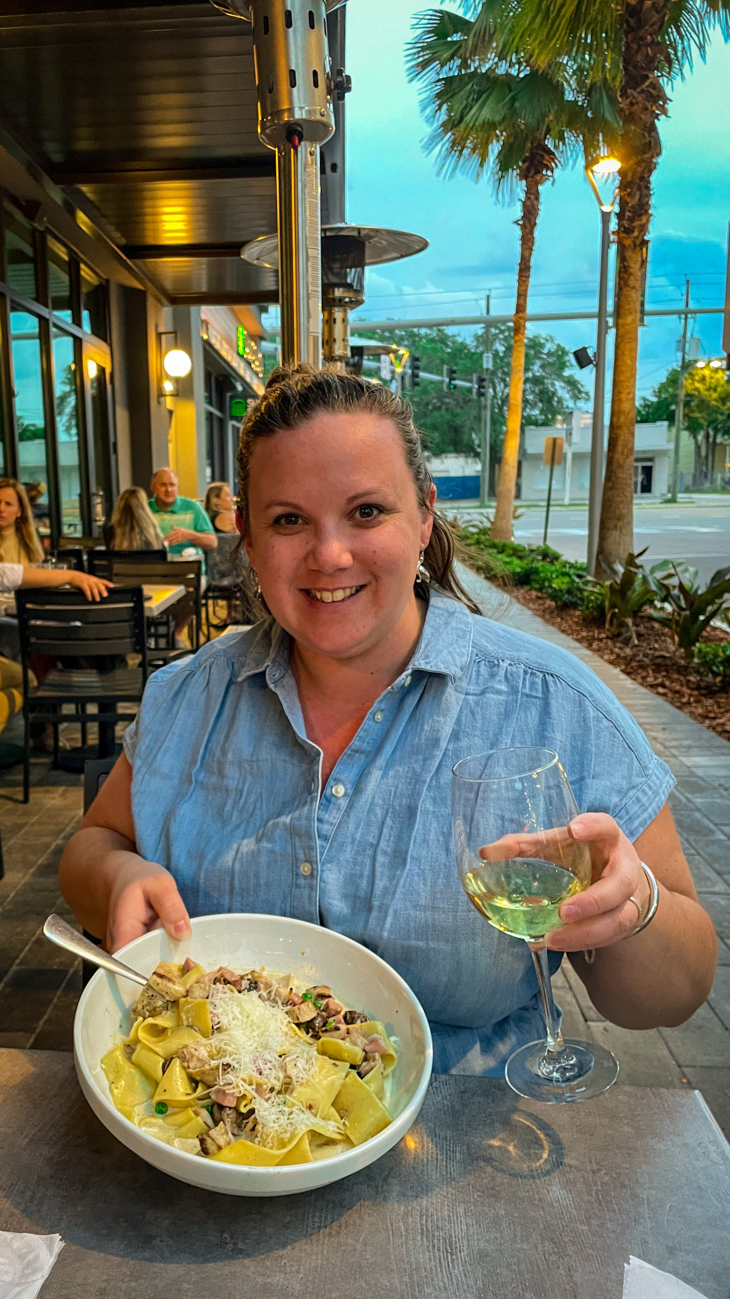 A woman holds her plate of pasta and a glass of wine, while dining at Bellabrava in Tampa Bay.