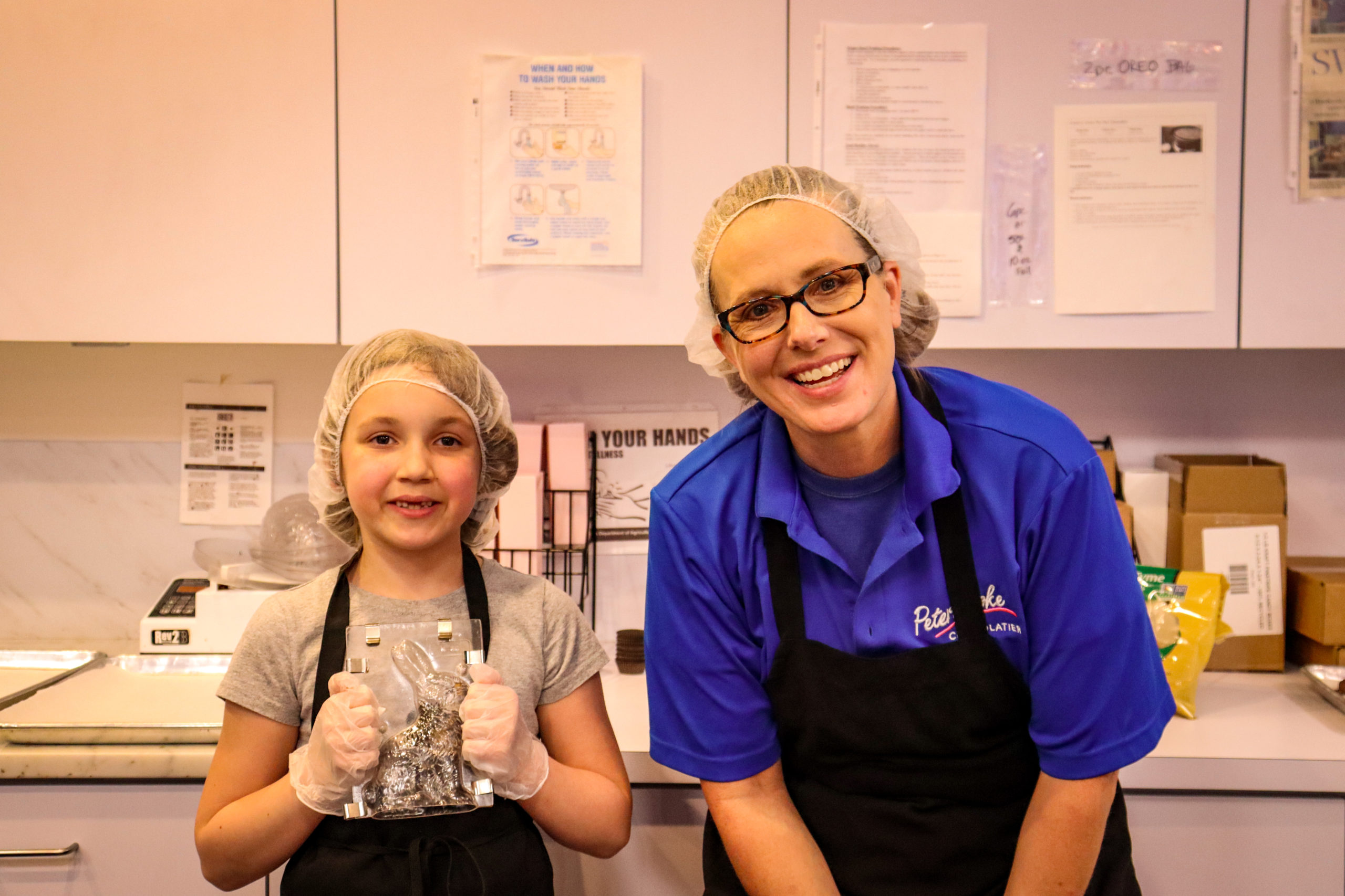 A young girl poses with a chocolate mold and the owner of Peterbrooke Chocolatier Tampa Downtown.