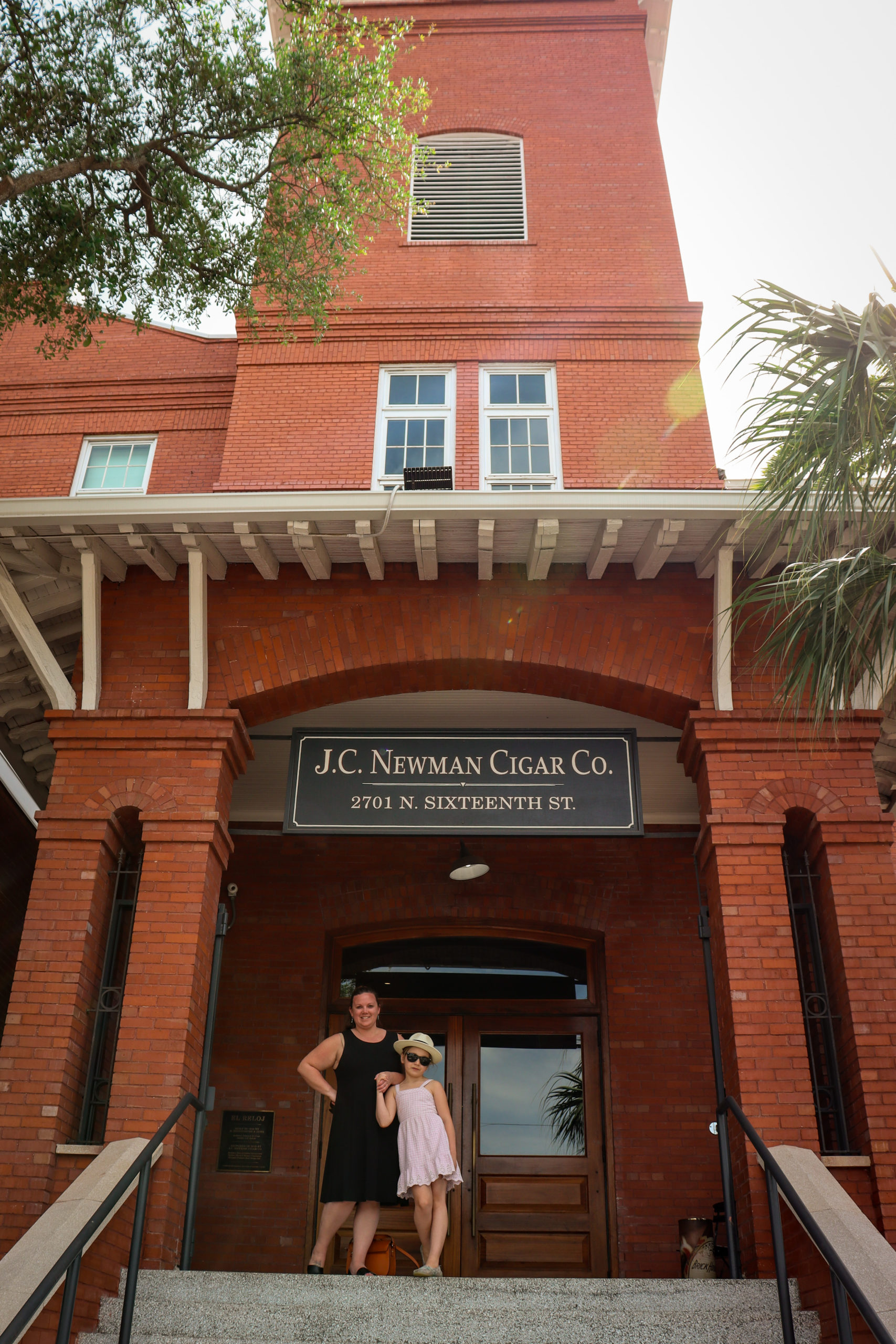 A young girl and her mom stand on the exterior steps of the J.C. Newman Cigar Co. in Ybor City.