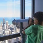 A young African American boy uses a view finder to look out on the Chicago skyline from the Skydeck.
