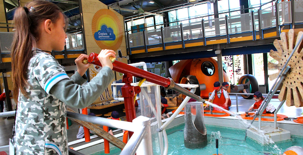 A young girl uses the water spray gun at the water table at Explora il Museo dei Bambini di Roma, one of the best museums in Rome with kids.