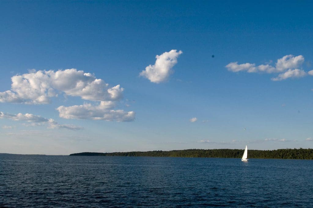 A sail boat moves across Leech Lake on a sunny day.