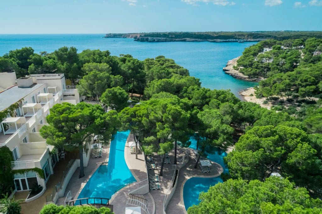 An aerial view of the shaded pool and grounds of Iberostar® Club Cala Barca, one of the best all-inclusive hotels in Mallorca for families.