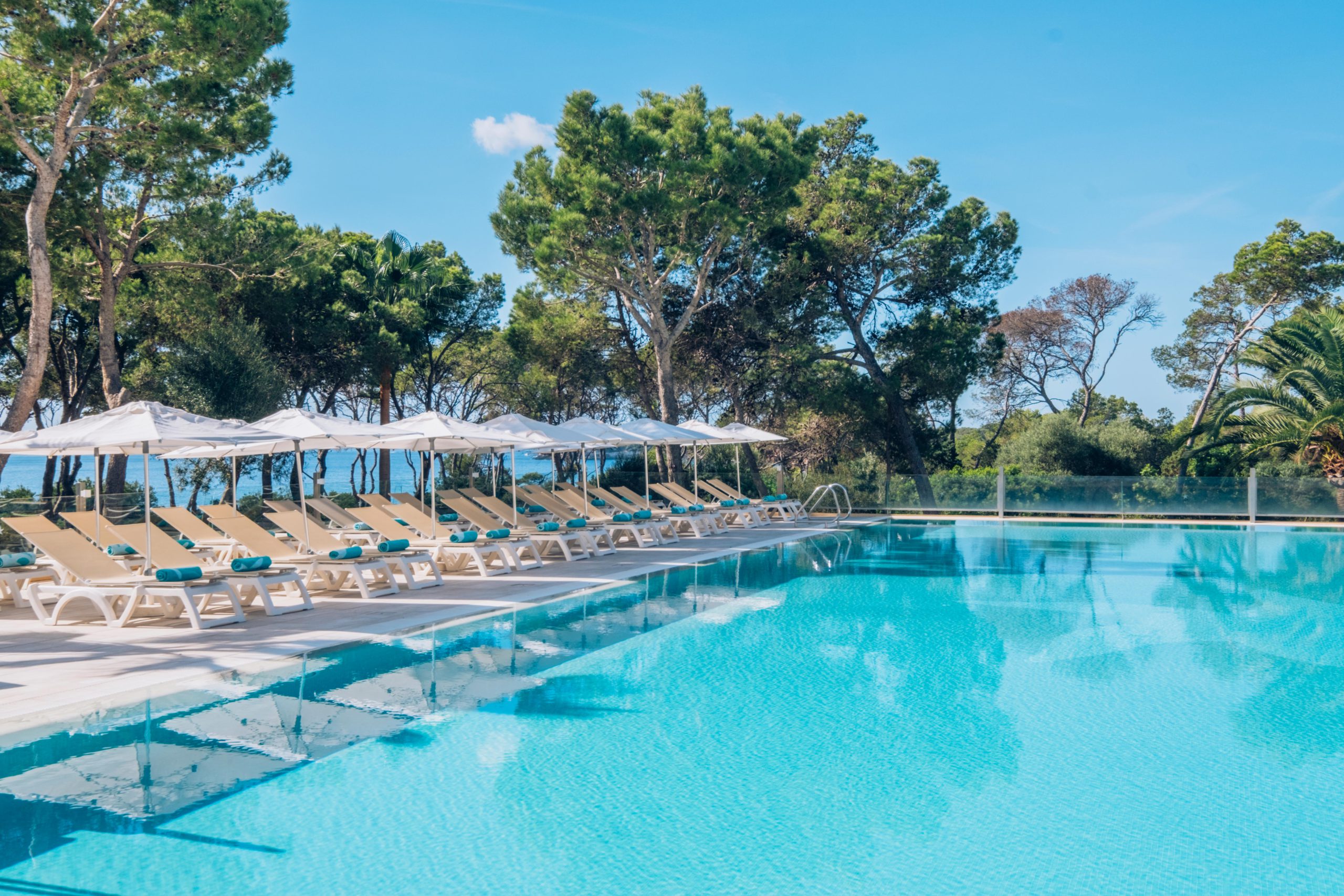 A serene pool and surrounding pool deck with loungers at Iberostar® Club Cala Barca, one of the best all-inclusive hotels in Mallorca for families.