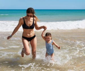 A mom and her young daughter splash in the waves in Mallorca, while staying at an Iberostar property.