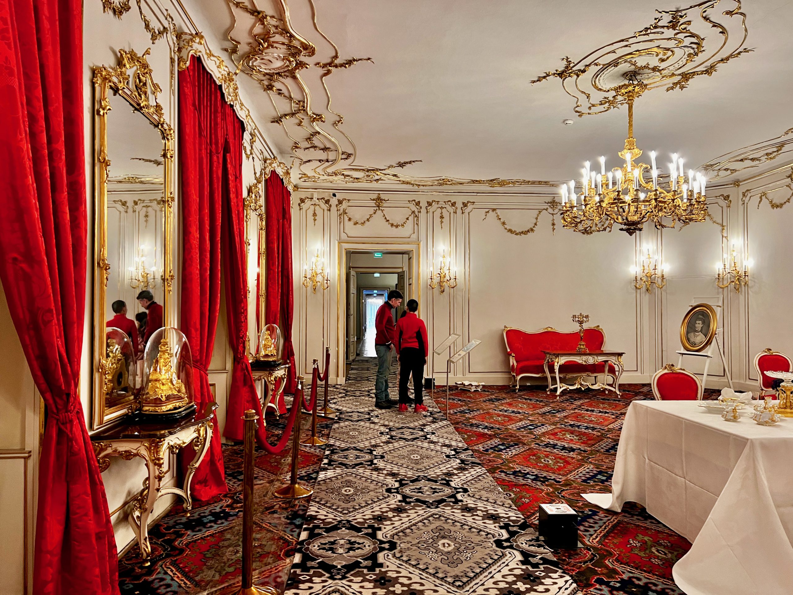 A dad and his young son look at the opulent furnishings of a richly decorated room in the Imperial Palace, one of the best things to do in Innsbruck with kids this winter.