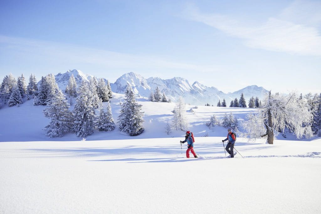 Two people trekking on snowshoes, while enjoy a sunny winter day near Innsbruck.