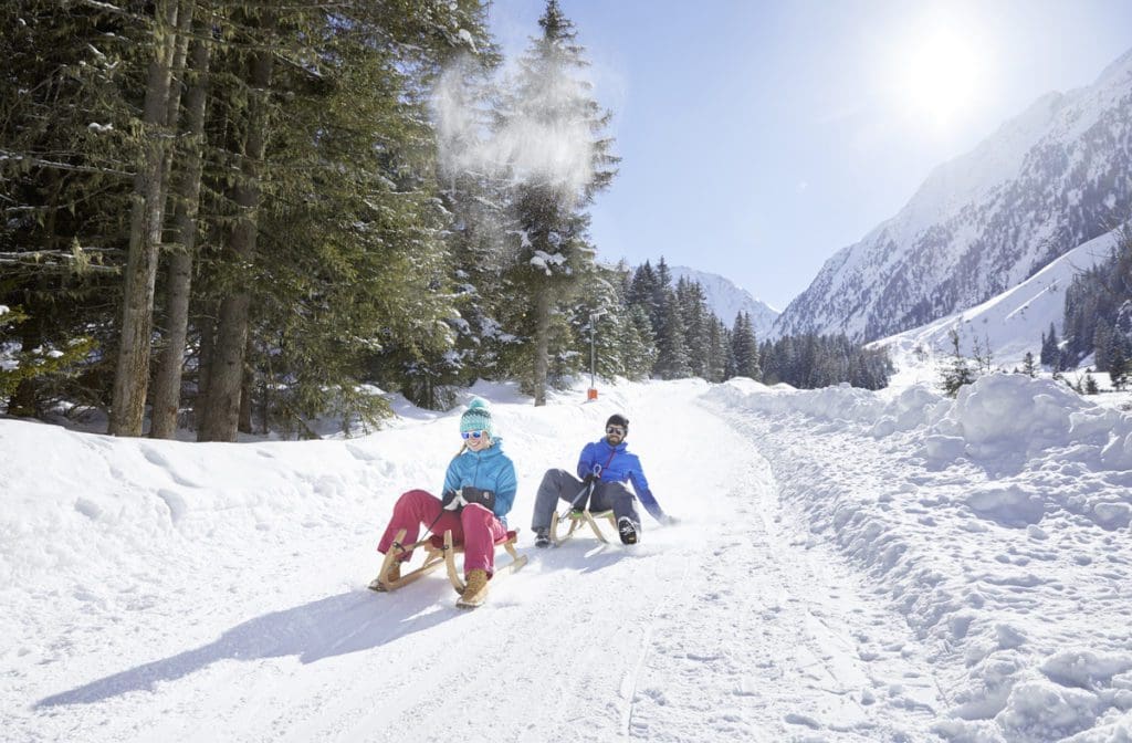Two people tobogganing in Gleirschalm on a sunny winter day, one of the best things to do near Innsbruck with kids this winter.