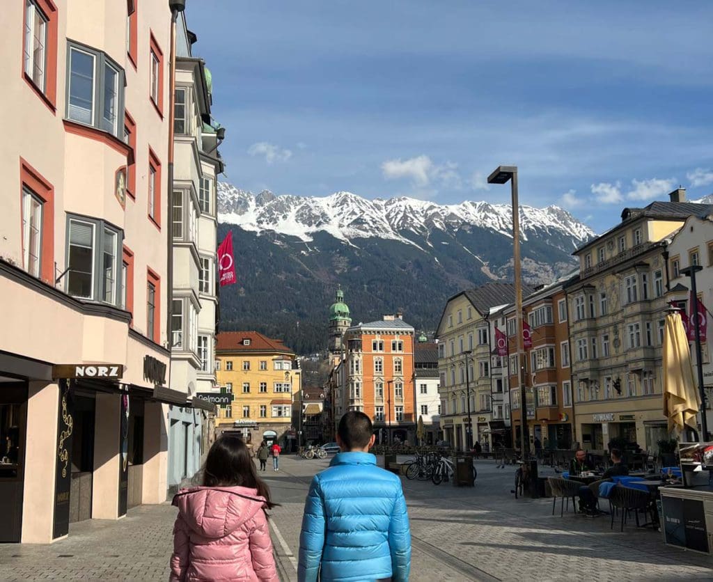 Two kids look toward Innsbruck's historic old town, while exploring the city as a family, one of the best things to do on this family guide to skiing in Kühtai this winter.