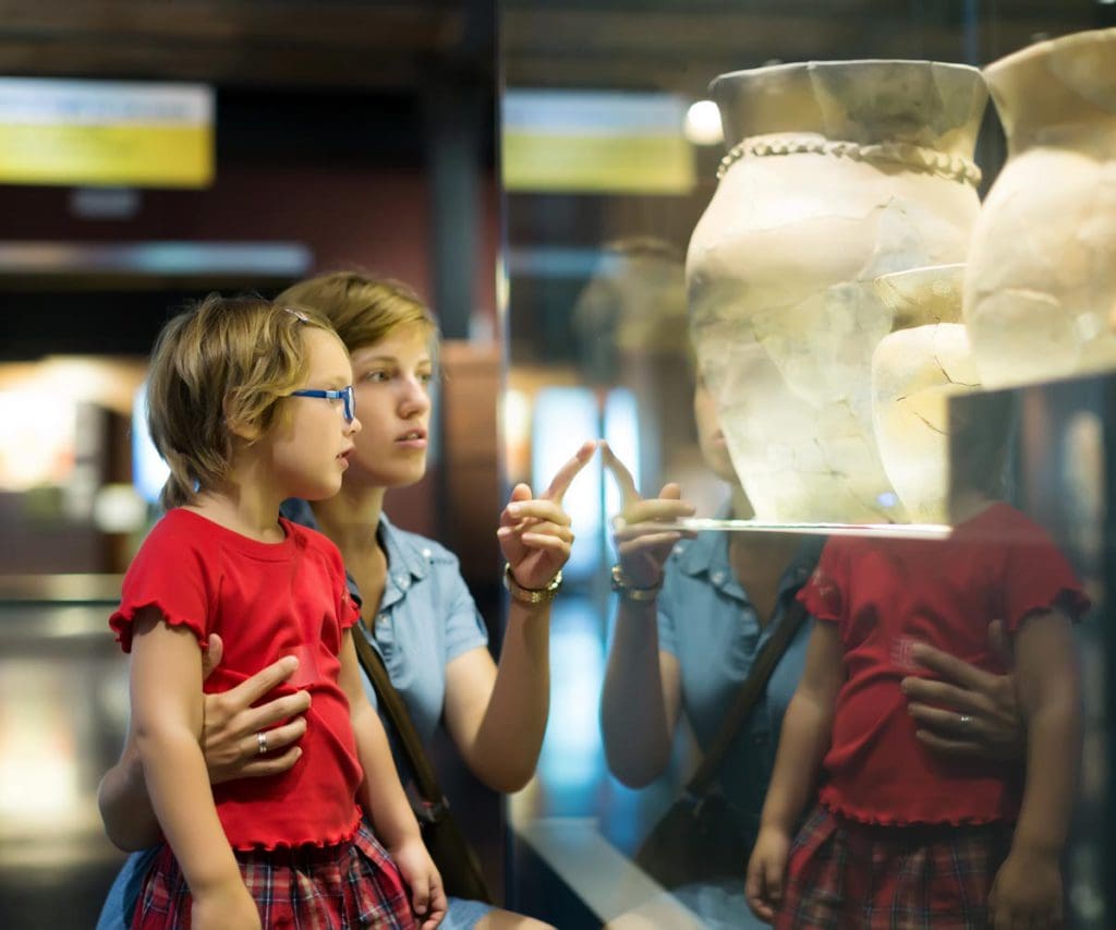 A mom and her young daughter look at ancient pottery at a museum in Rome.