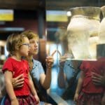 A mom and her young daughter look at ancient pottery at a museum in Rome.