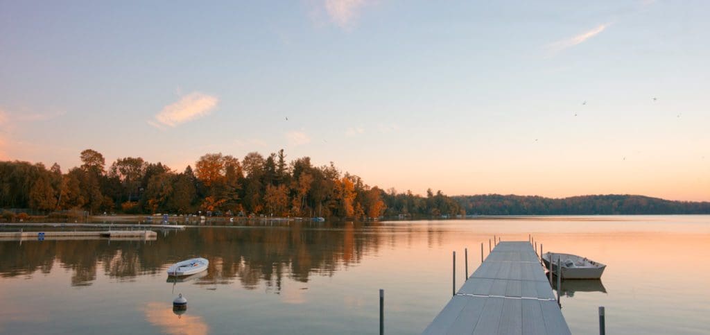 A dock stretches in Elkhart Lake, while the sunsets on the lake.