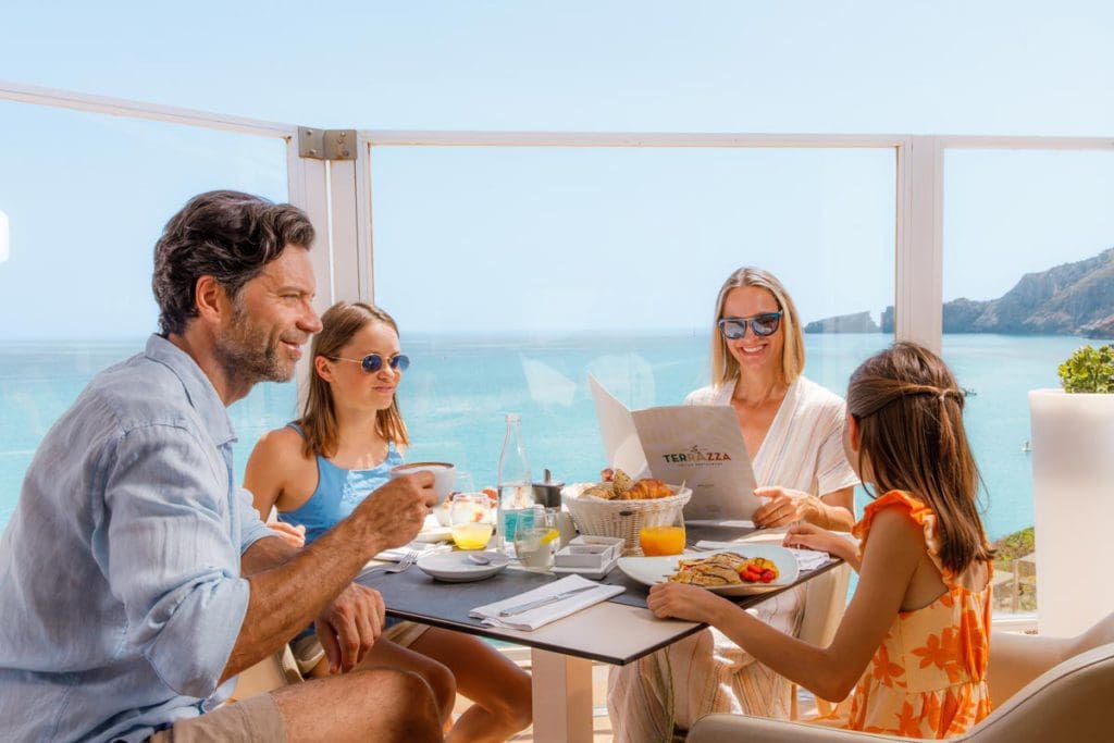A family of four enjoys a lovely breakfast together with a view of the sea, while staying at VIVA Cala Mesquida Resort & Spa, one of the best all-inclusive hotels in Mallorca for families.