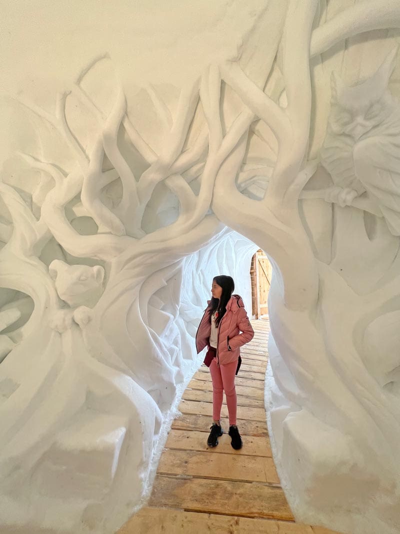 A young girl walks through a decorative igloo with several snow carvings at Top of Innsbruck, one of the best things to do with kids.