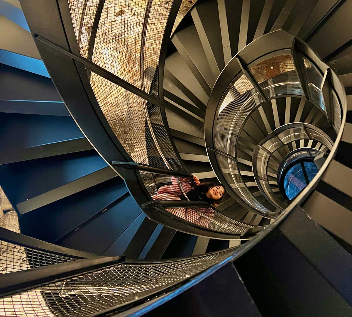 A young girl looks down as she climbs the circular staircase to the Innsbruck City Tower, one of the best things to do in Innsbruck with kids this winter.