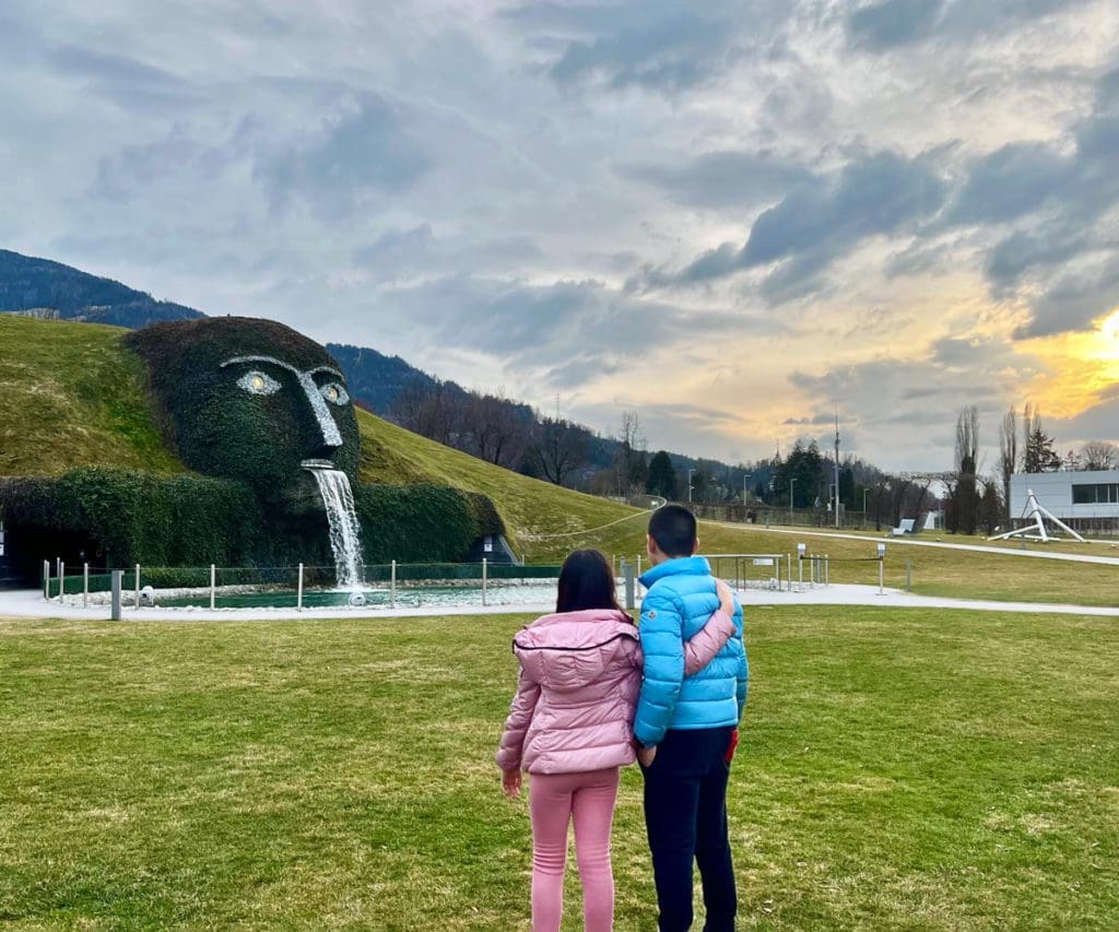 Two kids stand outside looking at the grass sculpture at the Swarovski Crystal World near Innsbruck, one of the best destinations in Austria with kids.
