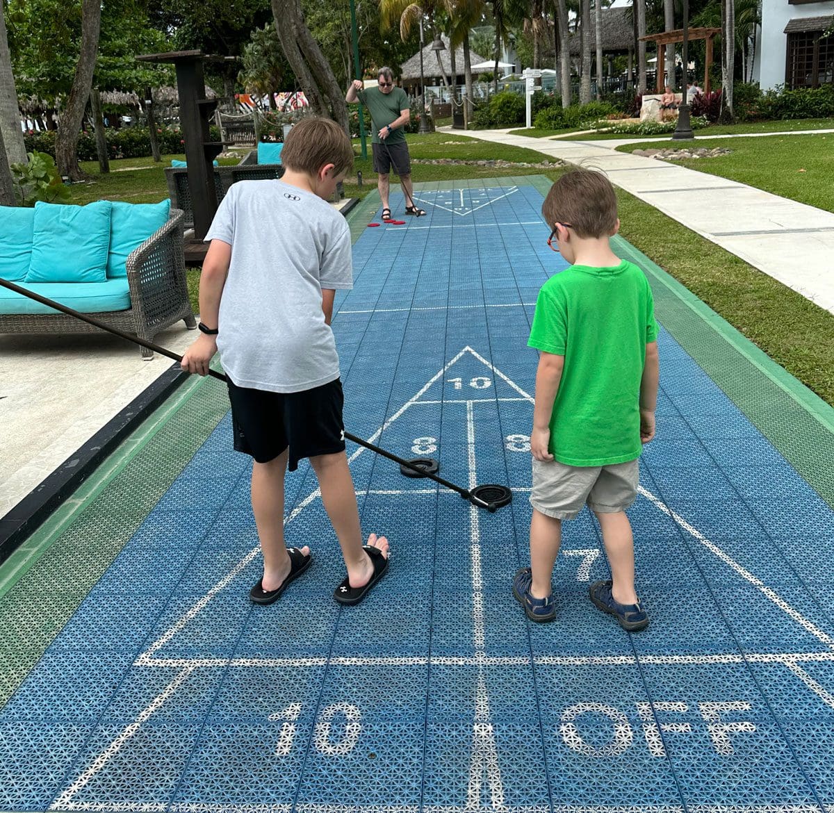 Two young boys challenge their parents to a game of shuffle board at Beaches Negril.