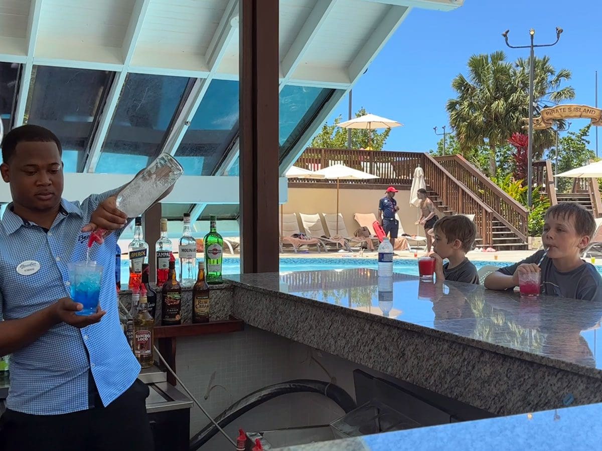 A bartender makes non-alcoholic drinks for two young boys at Beaches Negril.