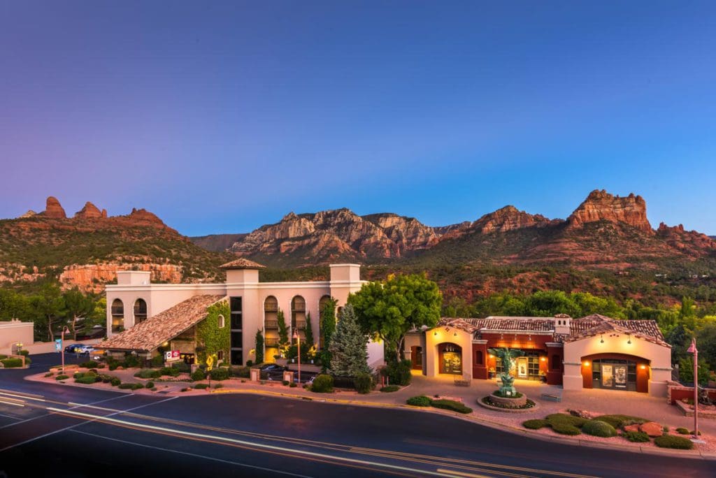 The exterior entrance of Best Western Plus Arroyo Roble Hotel & Creekside Villas with iconic Sedona red rocks in the distance.