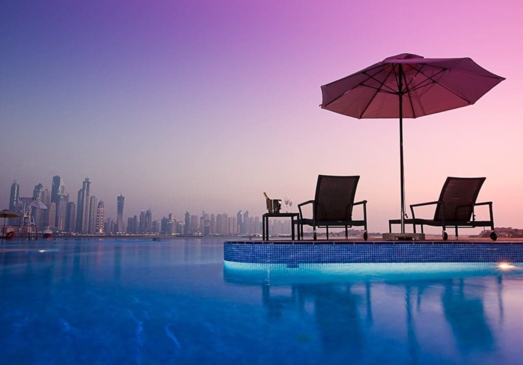 A pair of pool loungers at Dukes The Palm, a Royal Hideaway Hotel face the Dubai skyline.