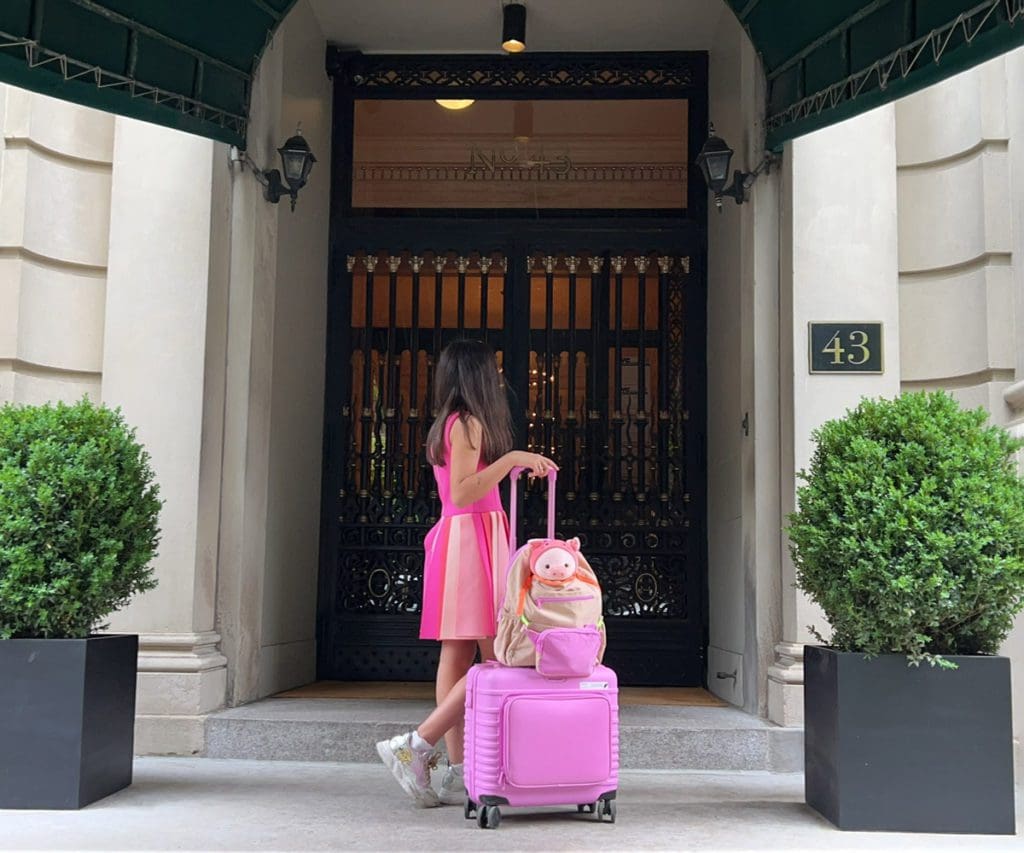 A young girl stands outside of an apartment in NYC with her pink BÉIS Kids Roller.
