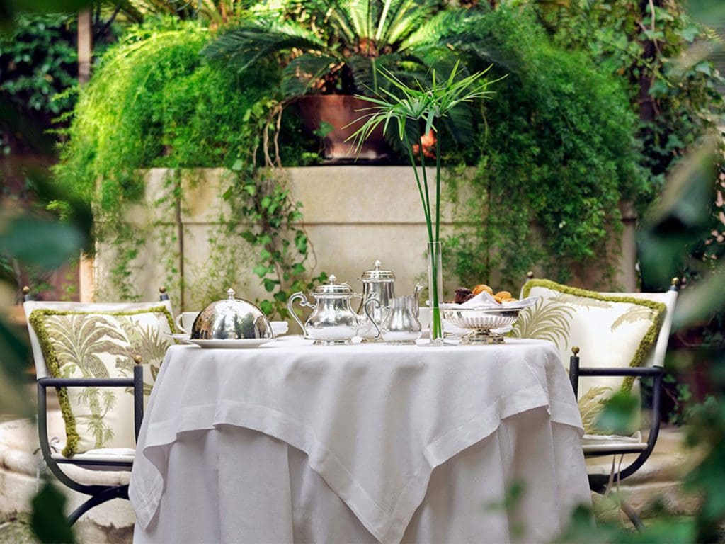 A table set for dinner in the lush outdoor patio at Hotel Metropole.