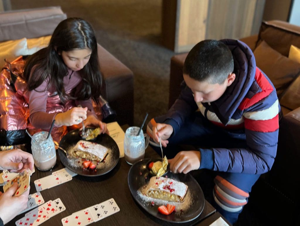 Two kids enjoy a snack in the lobby of Hotel Mooshaus, knowing where to stay is a is key apart to this family guide to skiing in Kühtai this winter.