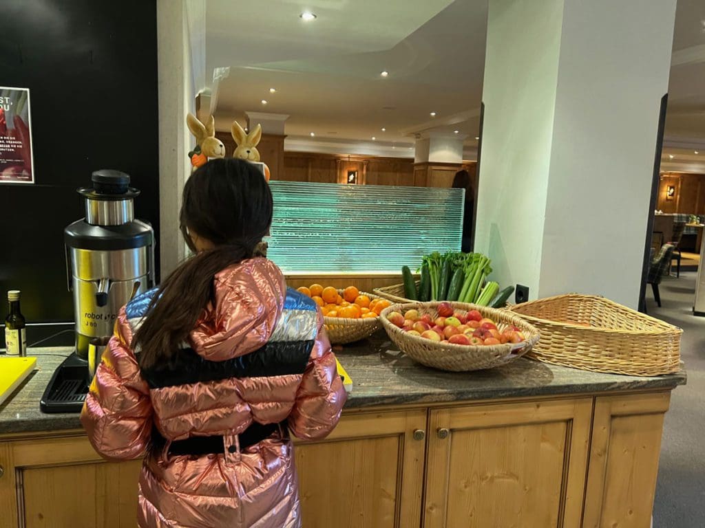 A young girl pours a breakfast juice while dining at Hotel Mooshaus, just one of the many reasons why families adore Hotel Mooshaus for a family ski vacation in Austria.