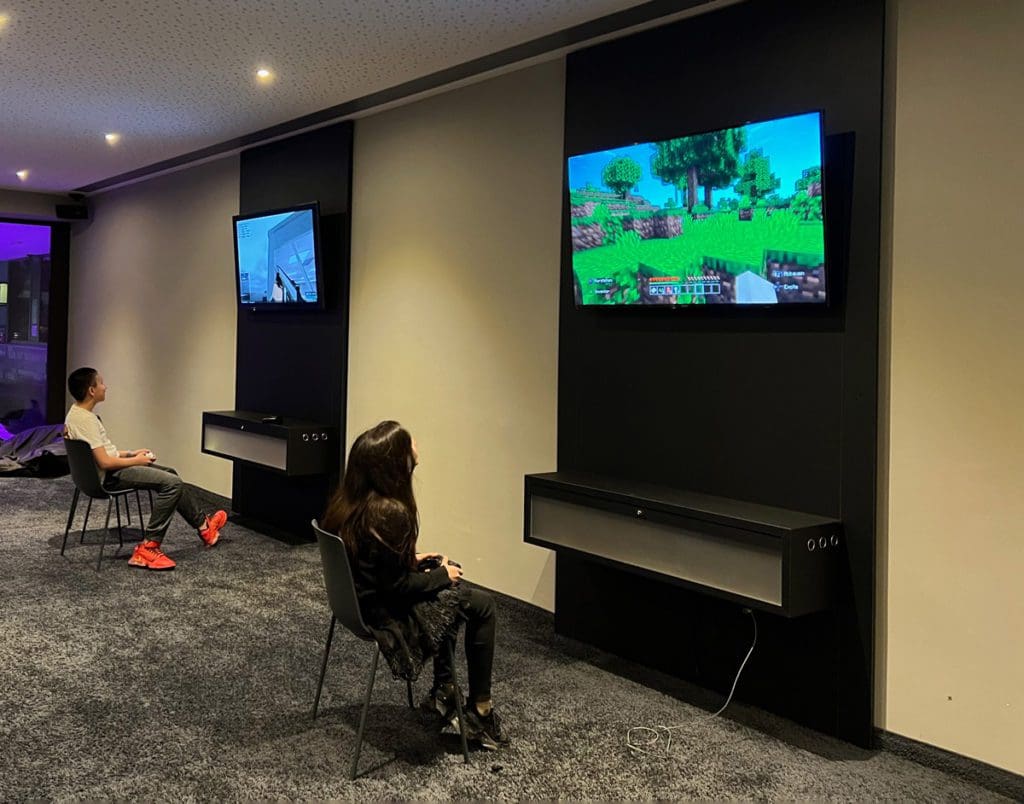 Two teens play video games at the hotel Teen Club, just one of the many reasons why families adore Hotel Mooshaus for a family ski vacation in Austria.