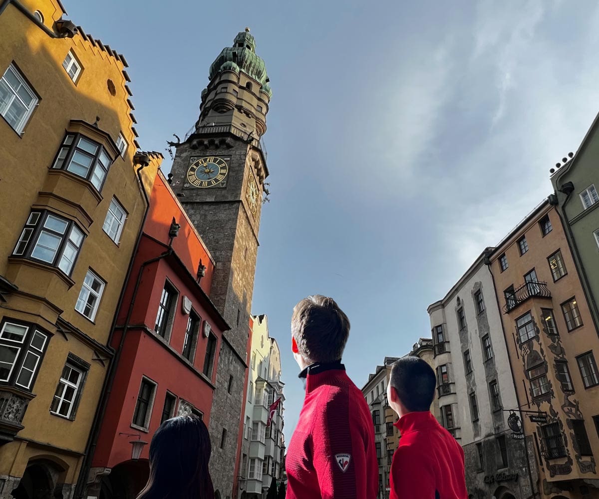 A dad and his two kids look up at Austrian alpine architecture while exploring Innsbruck together.