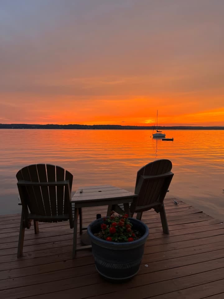 Two chairs face a brilliant sunset on Seneca Lake, one of the best lakes in New York State for families.