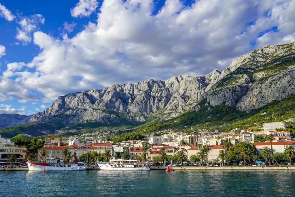 A view of the town of Makarska from across the water, with mountains in the distance.