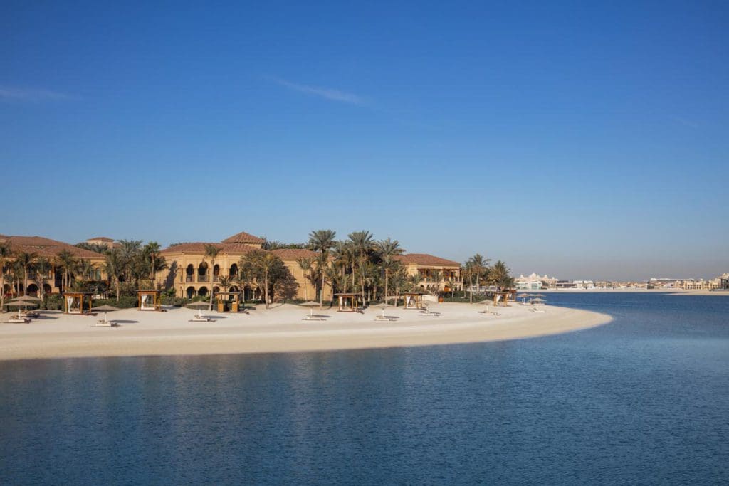 A view of the resort grounds and shoreline of One&Only The Palm, one of the best beachfront hotels in Dubai for families, from across the water.