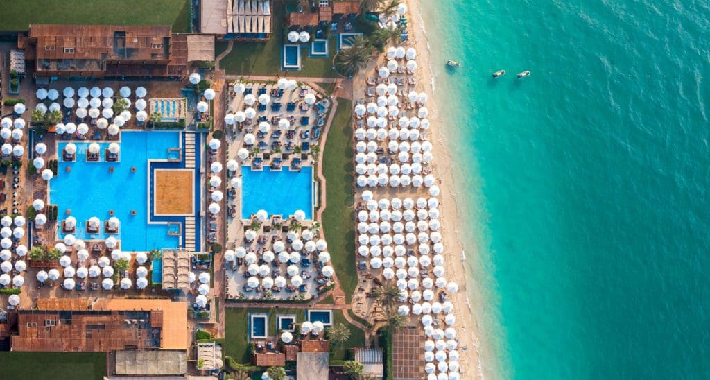 An aerial view of the beach, with beach cabanas, pool, and resort buildings at Rixos Premium Dubai JBR.