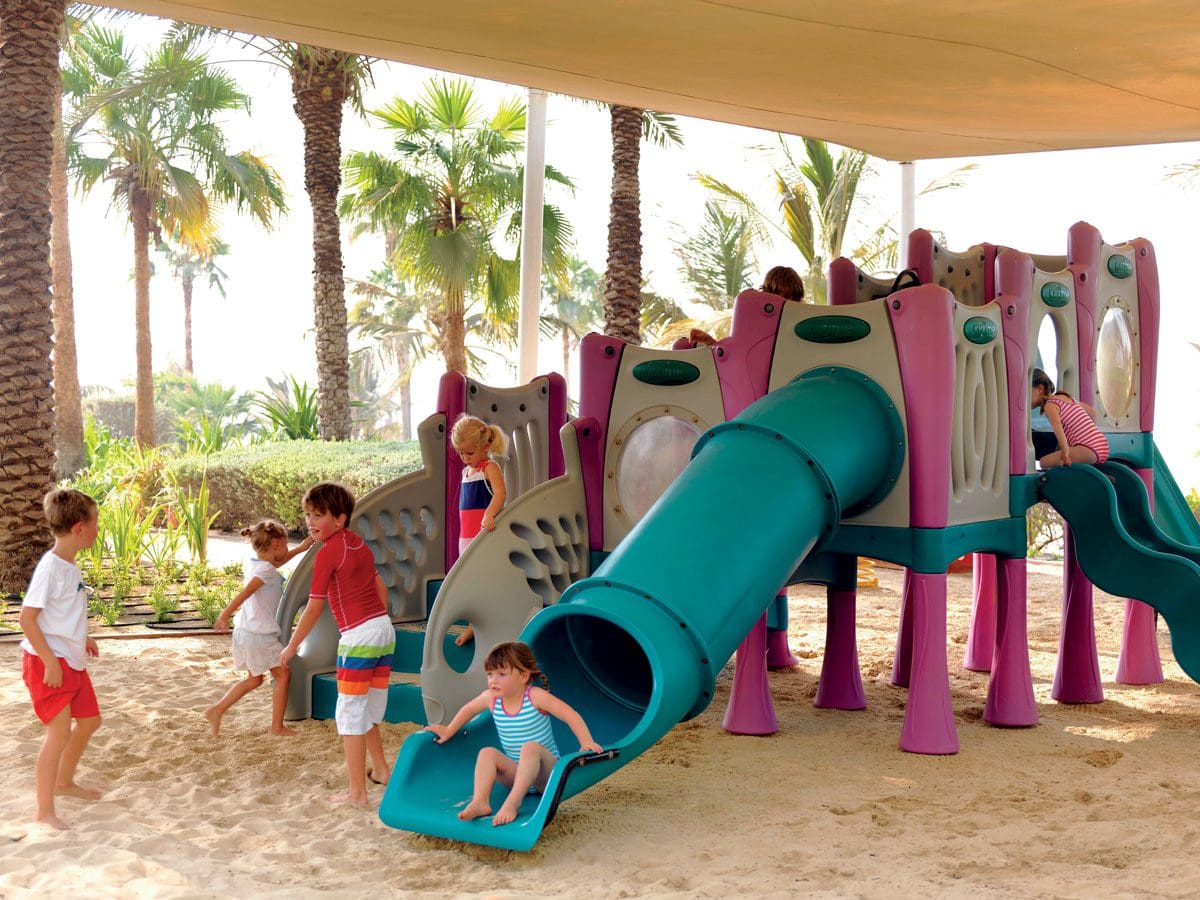 Kids play at the on-sight playground on the beach at The Ritz-Carlton, Dubai, one of the best beachfront hotels in Dubai for families.