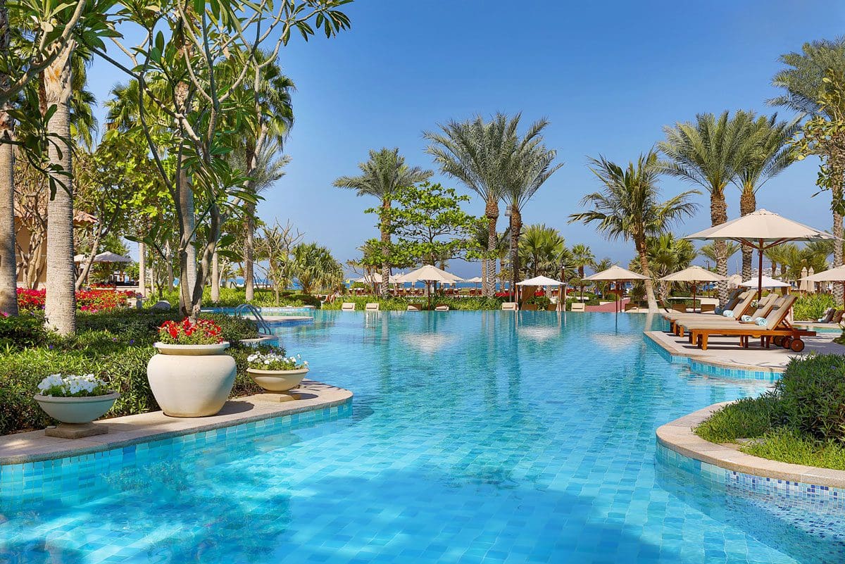 One of the beautiful pools, surrounded by lush greens, at The Ritz-Carlton, Dubai, one of the best beachfront hotels in Dubai for families.