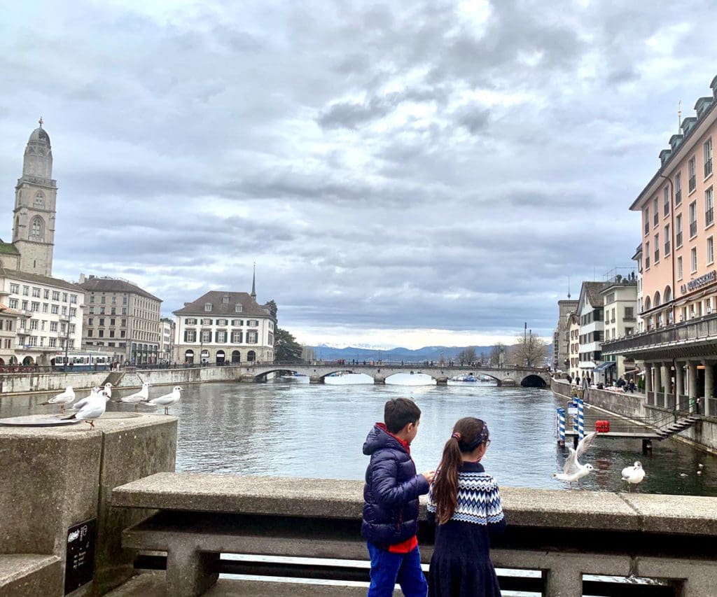 Two kids watch a seagull fly over a river in Zurich, Switzerland.