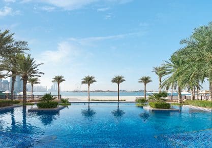 Several palm tress flank a pool at Fairmont The Palm.
