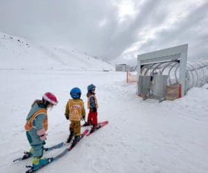 Three kids waiting to get onto a magic carpet while skiing in Kühtai.