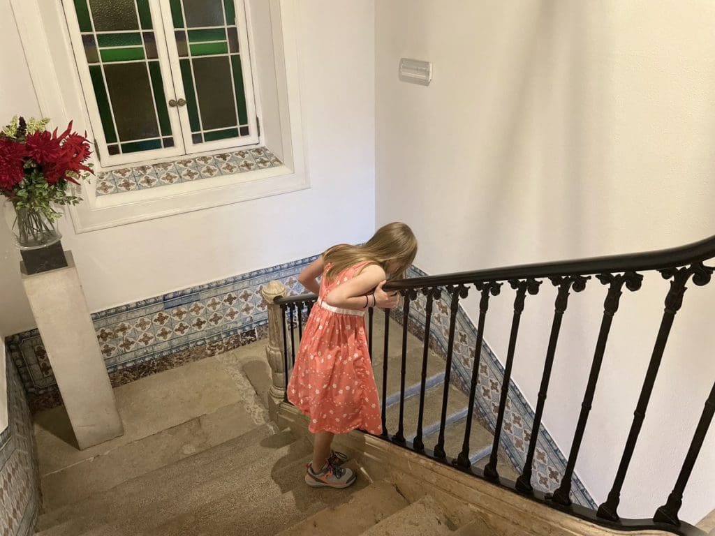 A young girl looks down a stairway at Alecrim ao Chiado - Once Upon a House.