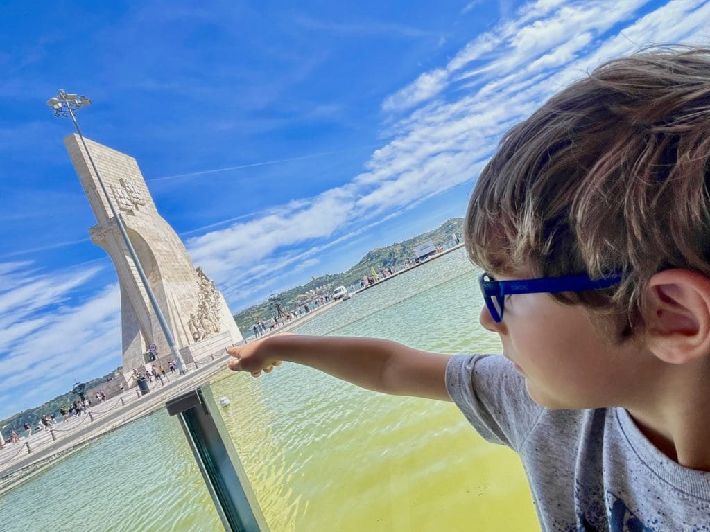 A young boy points to a statue while exploring Belem, a fun stop on any Lisbon itinerary with kids.