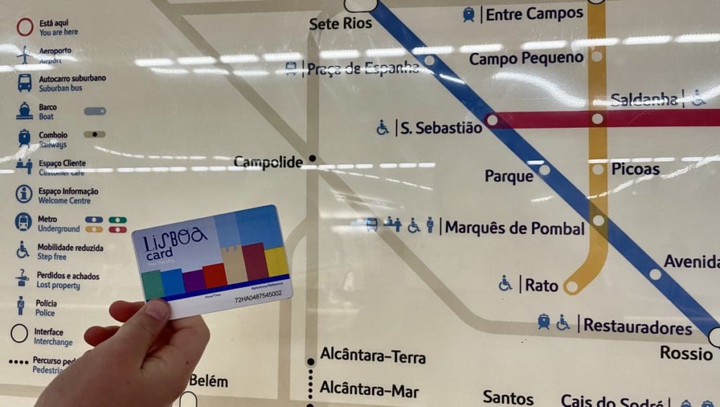 A hand holds out a Lisboa Card in front of a Lisbon metro map, a helpful thing to have on any Lisbon itinerary with kids.