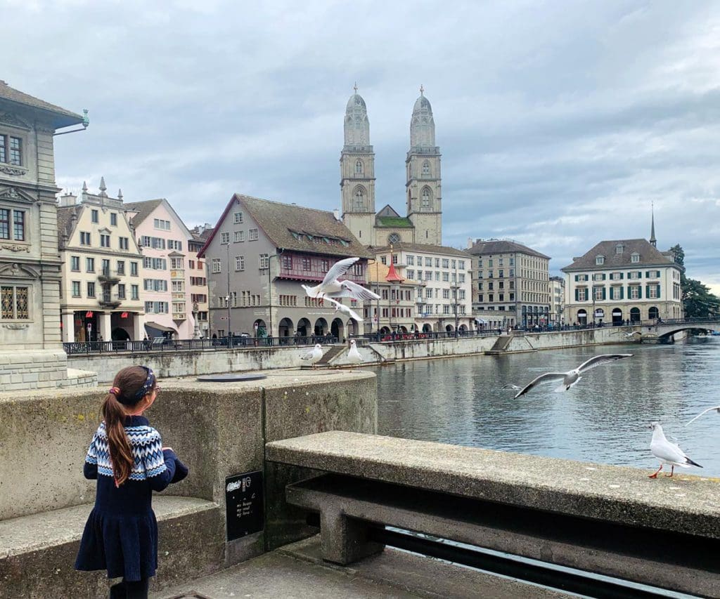 A young girl walks toward Lake Zurich, while exploring Zurich as a family, a must stop on any Switzerland itinerary with kids.